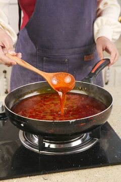 Chef Preparing Spicy Hot Pot Base with Traditional Wooden Ladle