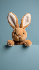 Obraz premium Cute Brown Stuffed Bunny Rabbit Peeking over Blue Background