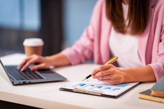 A young woman is analyzing finances, typing on a laptop, demonstrating the use of computers to process data quickly and accurately.
