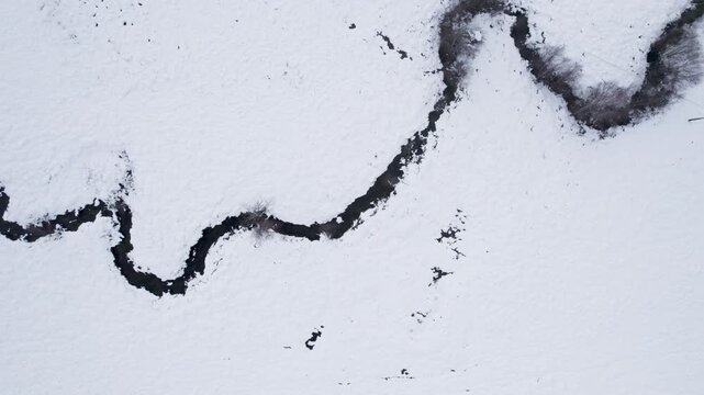 Aerial top down view of winding stream in snow The concept of minimalism