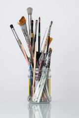 Dirty brushes in a glass jar on a white background