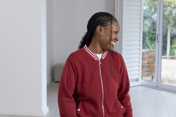 Sliding glass doors are revealing small patio and garden, sunlight casting across grey tiled floor