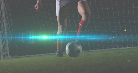 Standing soccer player on stadium turf, wearing red socks and black cleats with ball by goal