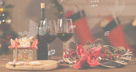 Showing holiday scene on wooden table at home, with two wine glasses, green bottle, wreath, cookies