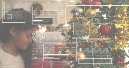 Naklejka premium Standing girl in sweater facing decorated tree at home with fireplace, gifts, HUD, copy space