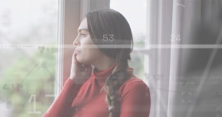 Fototapeta premium Standing woman with braid in red turtleneck gazing out window at blurred greenery, HUD overlays