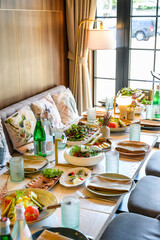 Lunch gathering at a restaurant with a diverse food spread on the table. People enjoy a lunch gathering at a restaurant with various dishes and drinks on the table.