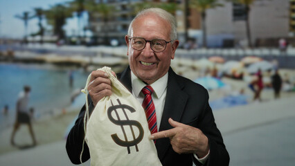 Senior man in business suit at seaside holding a money bag with dollar sign, suggesting wealth and...