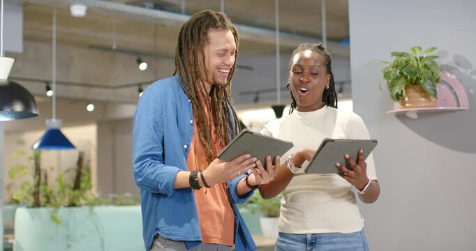 African American coworkers holding tablets at office, comparing content after one rotating tablet