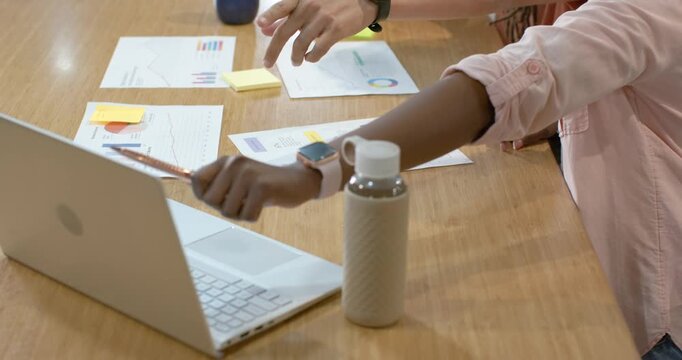Primary forearm is tapping pencil and pointing at laptop and charts, initiating planning discussion
