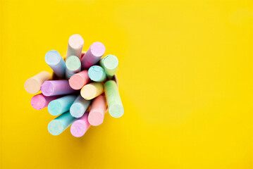 A bunch of pastel chalks on a bright yellow background for drawing and art projects in schools and creative activities