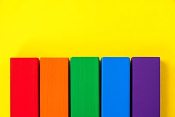 Colorful wooden blocks in rainbow colors on yellow background for decoration or education purposes  office supplies