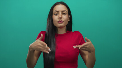 Woman meditating in front of an isolated green background, dressed in a red shirt, with long black...
