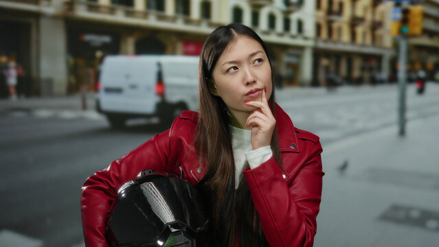 Woman in red jacket ponders on bustling city street holding helmet showcasing urban lifestyle and thoughtful expression in a vibrant outdoor scene.