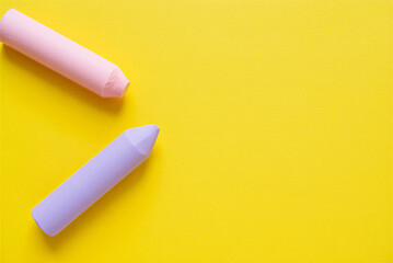 Two colorful chalks on yellow background for drawing and art  educational supplies
