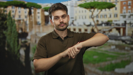 Young hispanic man checking wrist with hands at roman ruins outdoors near ancient columns;...