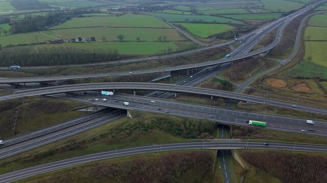 Aerial view of the intricate M1 M6 motorway junction, a network of roads cutting through the landscape with vehicles, Swinford, Northampton, United Kingdom.