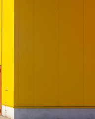 Bright yellow wall of a commercial building in a urban area with simple design during daytime