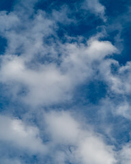 Clouds float in bright blue sky above during daytime hours in a clear atmosphere with scattered formations