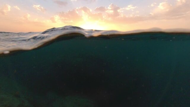 Underwater part and sunset skylight splitted by waterline, underwater bubbles. Beautiful clouds and bright sun over sea water, Real image very suitable for backgrounds in Mediterranean sea, undersea.