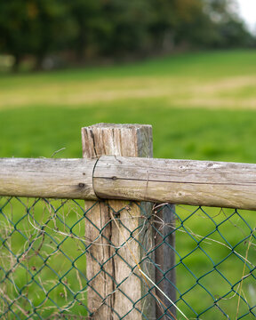 Wooden fence marks boundary in open green field during daylight in a rural area