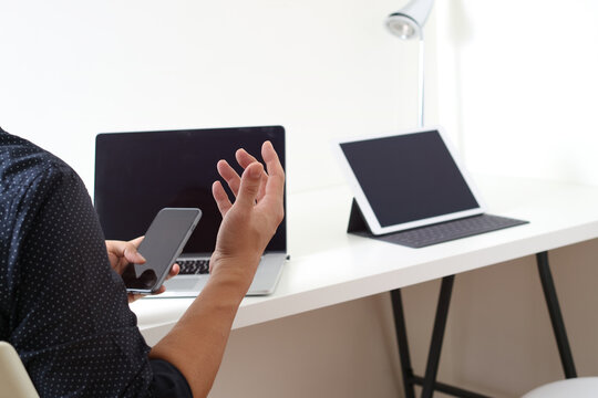 Business professional using smartphone with laptop and tablet at desk - Powered by Adobe
