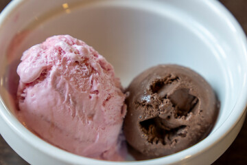 White bowl with two scoops of ice cream, one chocolate and one strawberry