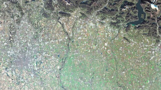 Satellite frame capturing Milan&rsquo;s outer districts and surrounding industrial and residential zones in 2026. The composition emphasizes land-use patterns, logistics corridors, and urban expansion