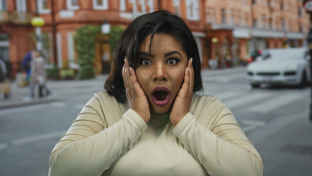 Woman on street shocked in city setting revealing surprised expression outside urban environment.