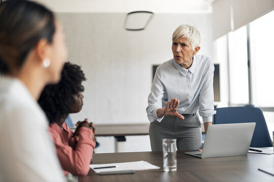 Female manager having intense conversation with employees during meeting