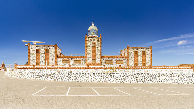 View of the stark white base of the lighthouse contrasts against the vibrant blue sky, a beacon of guidance against the vast ocean horizon, La Oliva, Canary Islands, Spain.