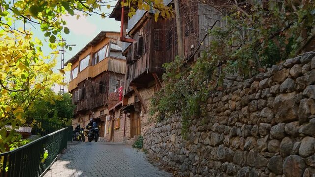 Motorcycle convoy riding through a village road in Erzincan, Turkey. Traditional houses, stone walls and autumn trees create a scenic rural atmosphere ideal for travel, adventure and cinematic road tr