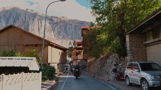 Motorcycle convoy riding through a village road in Erzincan, Turkey. Traditional houses, stone walls and autumn trees create a scenic rural atmosphere ideal for travel, adventure and cinematic road tr