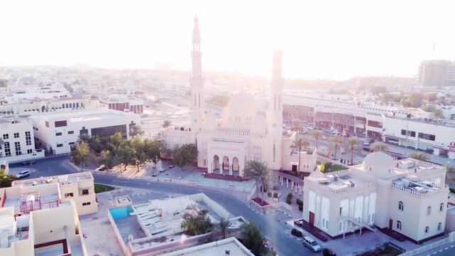 Cinematic view of Jumeirah Mosque at sunset with warm golden hour light on white stone minarets, iconic Fatimid style architecture near La Mer beach in Dubai.