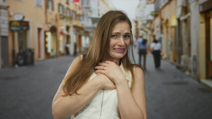Fototapeta premium Woman clutch chest in street with agonized expression and tearful gaze amid blurred city buildings and distant passersby; pain.