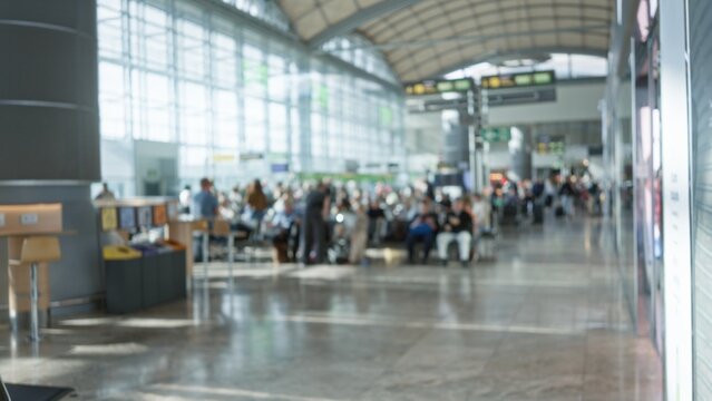 Busy airport terminal with defocused travelers sitting and waiting under arched ceilings in a bright modern waiting area with blurred architecture and bokeh effects