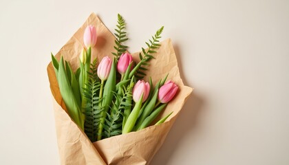 Fresh pink tulips and greenery arranged in paper bouquet  
