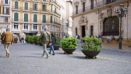Street scene in a european town with blurred pedestrians walking past beautiful historic buildings, highlighting a vibrant urban landscape under a clear sky.