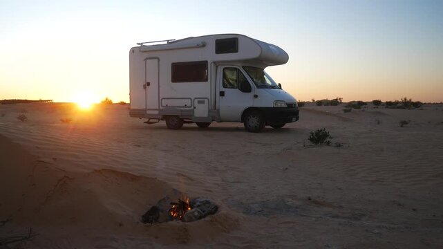 Off-grid camper van at sunset in the desert with a glowing campfire, symbolizing van life, freedom, outdoor living, slow travel, and a peaceful nomadic lifestyle.