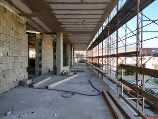 Interior of a construction site with a reinforced concrete structure under construction. Concrete blocks are neatly stacked on the floor, between load-bearing pillars and walls under construction.