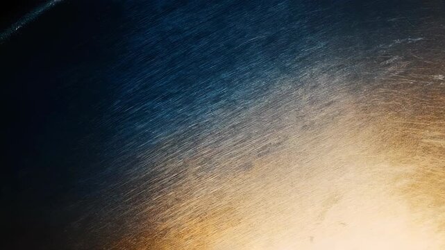 A dark textured surface transitions from deep blue to warm golden hues