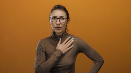 Obraz premium Woman showing shocked expression on orange background with glasses, wearing brown shirt, exhibiting surprise and emotion, isolated for expressive communication and illustrative content.