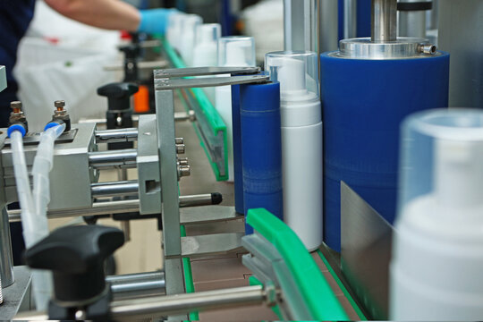 Bottles without labels on the conveyor of a cosmetics factory. Manufacture of cosmetics and skin care products. A white plastic bottle.