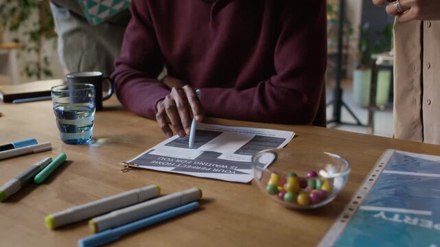 Close-up tilt-up shot of group of diverse designers working on documetns at desk in modern bureau office