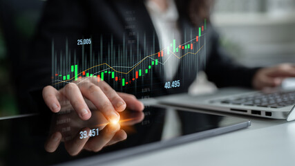 A business professional uses digital tools to analyze stock market trends, focusing on graphs and...
