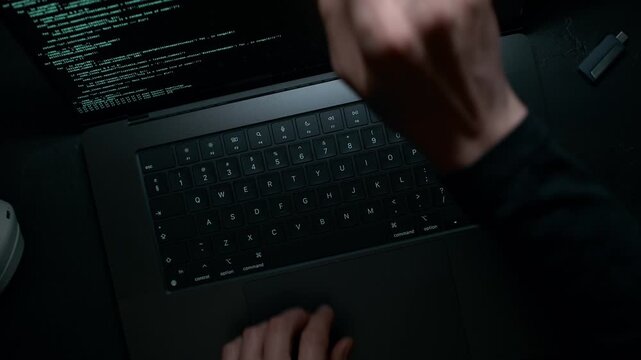 Programmer Coding on a Laptop Finishes Work and Closes the Device with His Hand, Dolly in to a Black Casing, Overhead View
