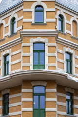 Fototapeta premium Historic brick building corner with green windows, renovated European architecture