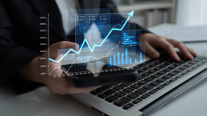 A business professional analyzes financial trends using a smartphone and laptop, emphasizing the importance of data-driven decision-making in today digital workspace. Scalp