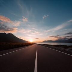 Scenic road leading to sunrise over mountain range and lake