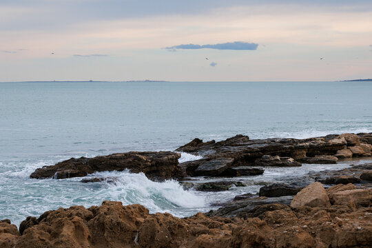 Paisaje mar&iacute;timo con tonos pastel del atardecer desde la playa de Agua Amarga y la isla de Tabarca en el horizonte, Espa&ntilde;a